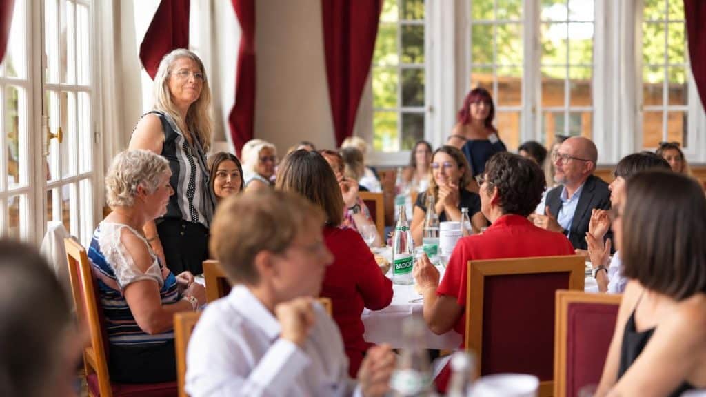 Participante debout, regards attentifs autour de la table