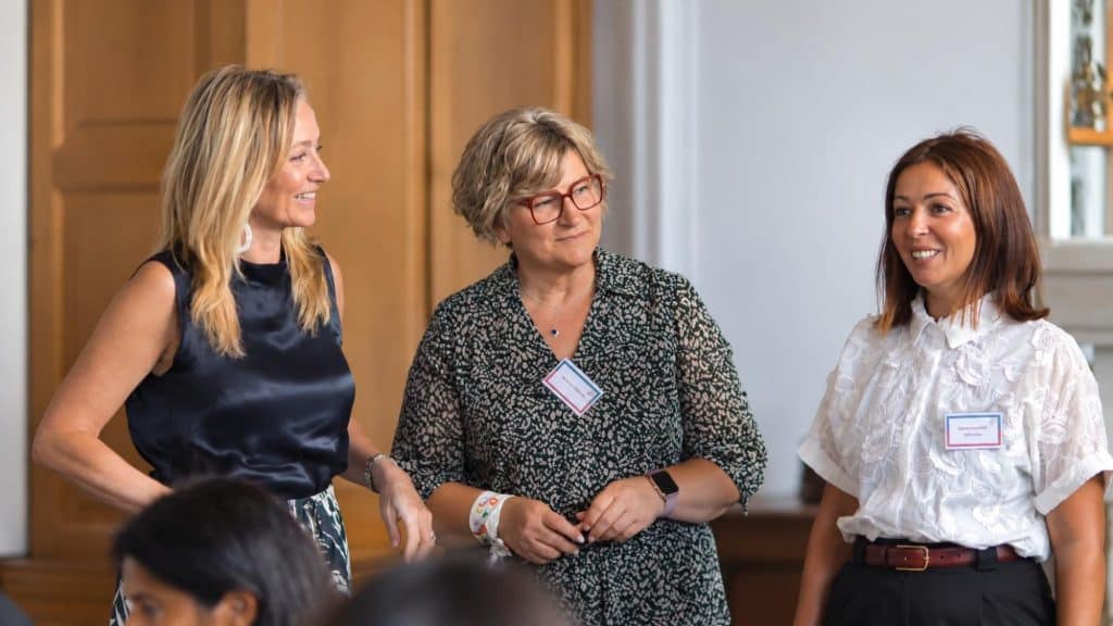 Trois participantes souriantes dans la salle